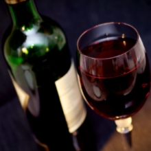 Glass of Red Wine Sitting Next to a Bottle of Red Wine